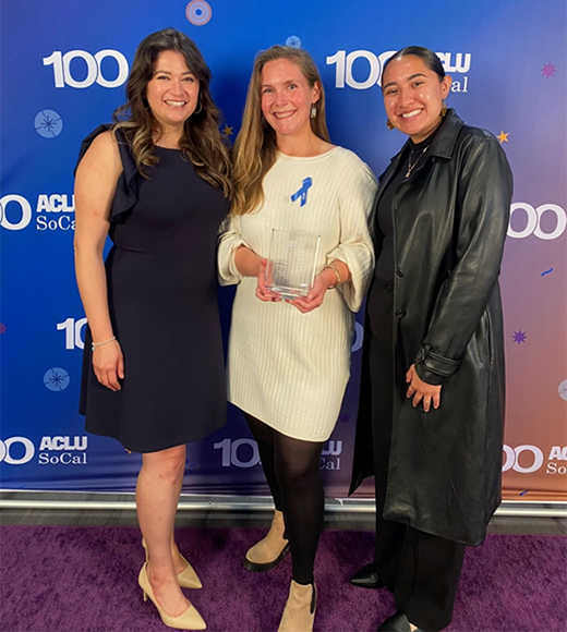 UCI Law Immigrant Rights Clinic students Sandra Guzman (’23, left) and Brenda Rosas (rising third-year student, right) pictured with former Clinical Fellow Caitlin Bellis (center) holding the award at the ACLU SoCal Advocates for Justice Reception. 